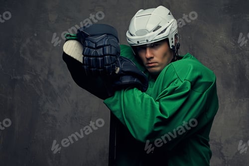 Preview: Hockey player wearing black protective uniform holds a hockey stick on a gray background.