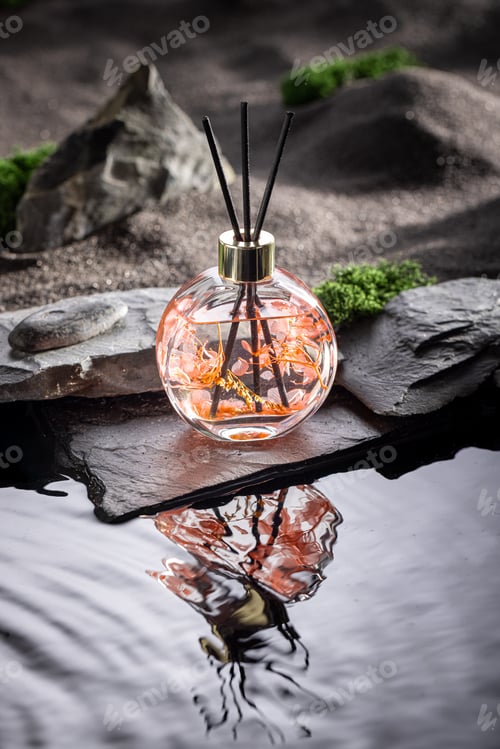 Preview: Intense fragrance diffuser reflecting in the water surrounded by stones.