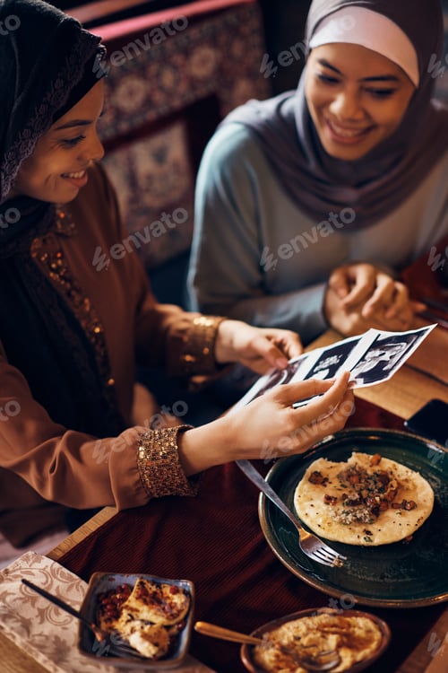 Preview: Happy Muslim women looking at baby ultrasound image during a meal dining table.