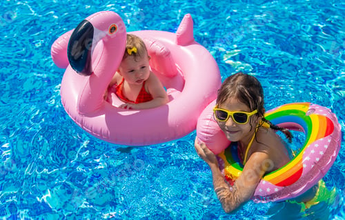 Preview: Sister's children swim in the pool. Selective focus.