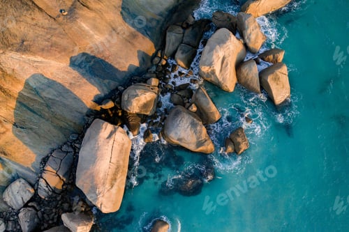 Preview: Aerial view of rocks on turquoise sea coastline.