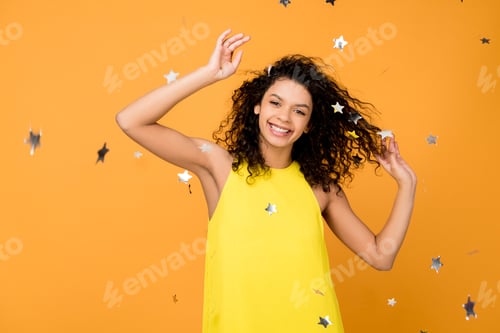 Preview: happy curly african american woman smiling near shiny confetti stars on orange