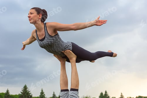 Vista previa: Close up of man lying on grass and balancing woman in his feet. Young couple