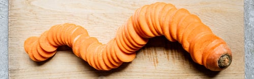 Preview: top view of fresh ripe carrot slices on wooden cutting board on concrete surface, panoramic crop
