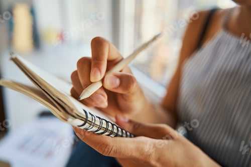 Preview: Woman dressed in casual clothes jotting down her ideas by the window