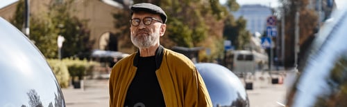 Preview: A dapper senior man embraces his trendy outfit while enjoying a leisurely walk.