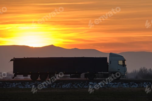 Preview: Semi-truck with cargo trailer driving on highway hauling goods in evening.