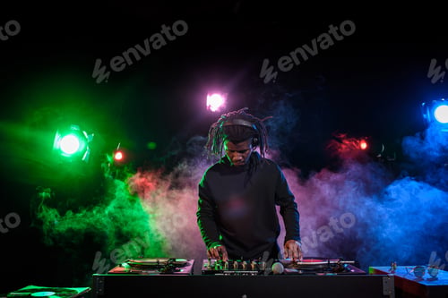 Preview: professional african american club DJ in headphones with sound mixer in nightclub