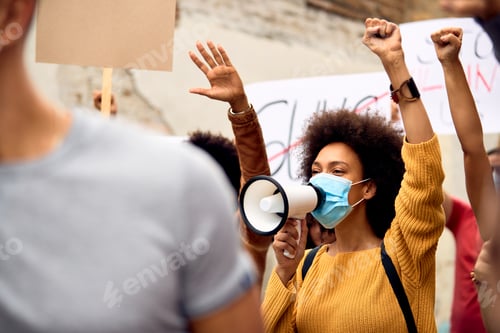 Preview: Young black woman wearing face mask while shouting through megaphone on anti-racism protest.