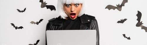 Preview: panoramic shot of shocked woman in wig looking at laptop in Halloween