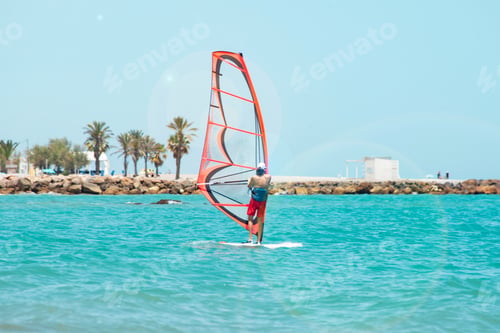 Preview: a man controls a sail on a surfboard in the sea against the background of the water and beach