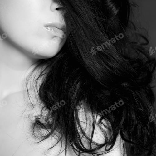Preview: Young woman with long hair against a dark background. shallow depth of field. bw image