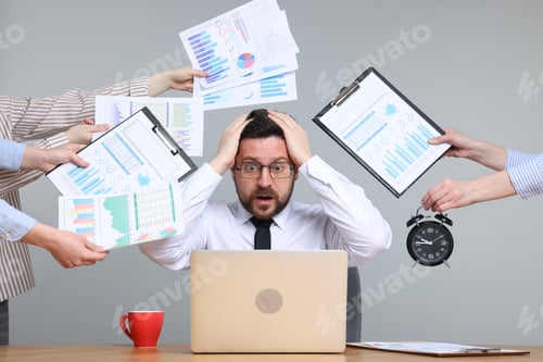 Preview: Man overwhelmed by different requests from colleagues at desk on light grey background