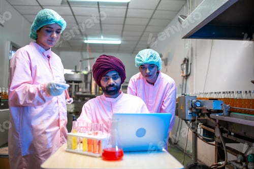 Preview: Asian scientists use test tube checking juice product in the beverage factory.