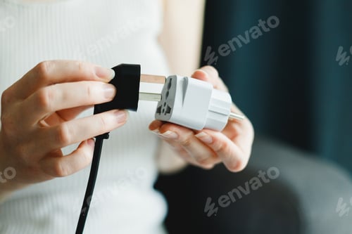 Preview: Woman applies universal travel adapter electrical plug converter power socket