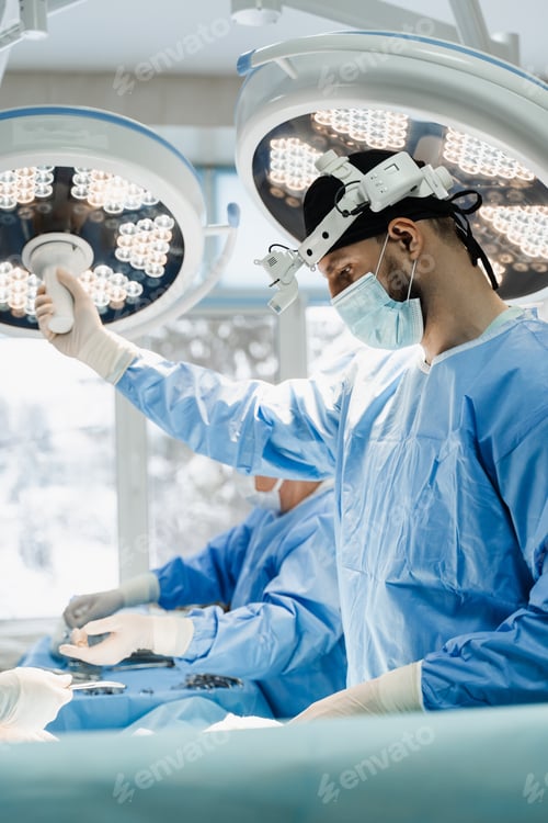 Preview: Surgeon holds operating lamp directing light on surgical field in medical clinic