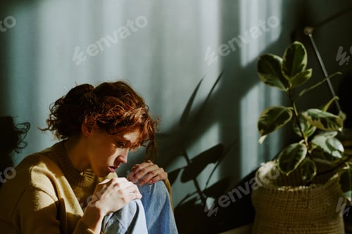 Preview: Contemplating Woman Sitting Next to Houseplant Indoors