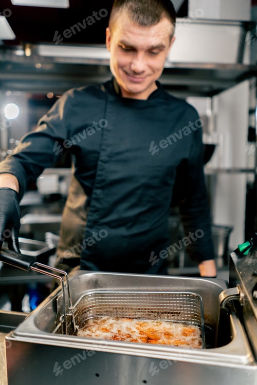 Preview: the chef in the kitchen smiles, holds a deep fryer and looks thoughtfully close-up sweet potato