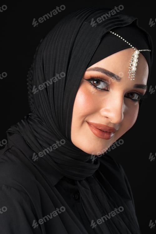 Preview: Woman wearing a black hijab with jewelry posing against a dark background