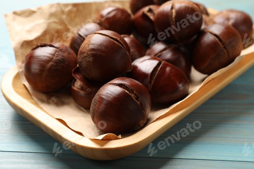 Preview: Fresh edible sweet chestnuts in serving plate on light blue wooden table, closeup