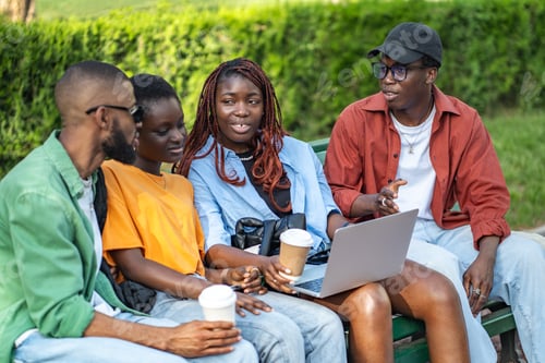 Preview: Interracial friends group enjoying coffee in park with laptops, chatting, relaxing and freelancing