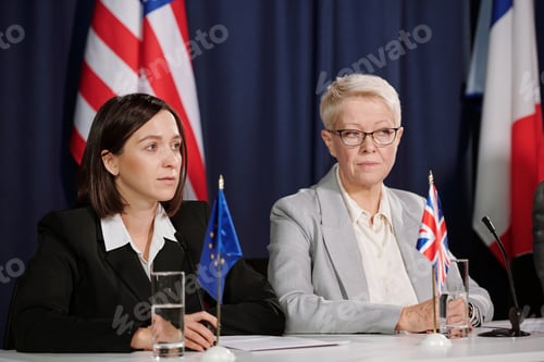 Preview: Mature and young female delegates in formalwear listening to other speaker