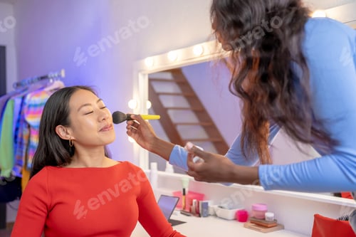 Preview: Makeup artist applying makeup to woman's face in front of a mirror