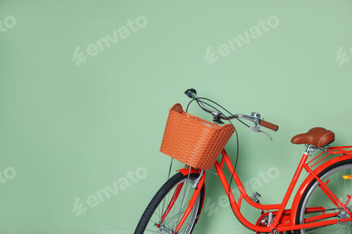 Preview: Red bicycle with basket near light green wall indoors. Space for text