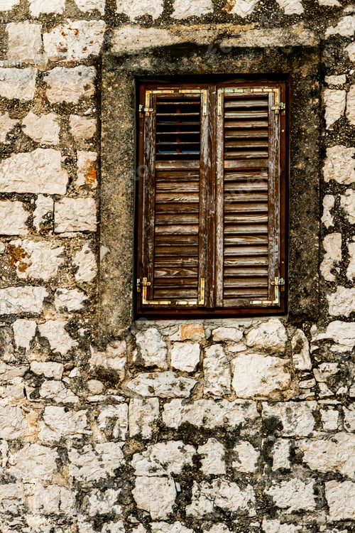 Preview: Stone wall and window with closed wooden shutters