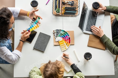 Preview: Overview of three young creative designers sitting by desk and choosing colors