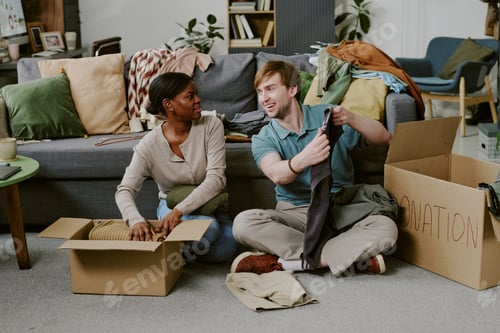 Preview: Multiethnic Adult Couple Sorting Clothes for Donation at Home