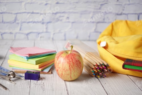 Preview: back to school concept with yellow backpack and school suppliers on table