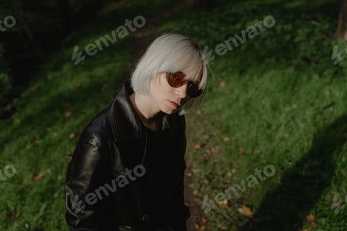 Preview: girl with blond hair in sunglasses on a green background looks at the camera