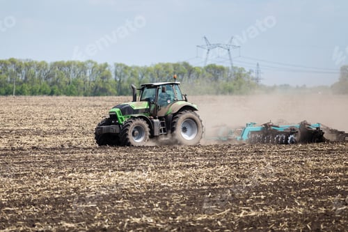 Preview: Tractor preparing soil for planting in rural farmland during spring