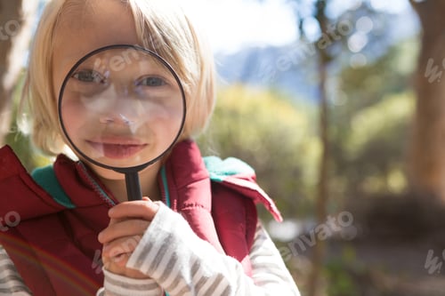 Preview: Little girl looking through magnifying glass in the forest