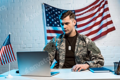 Preview: handsome soldier in uniform using laptop in office