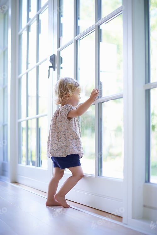 Preview: Portrait female toddler looking out of patio doors