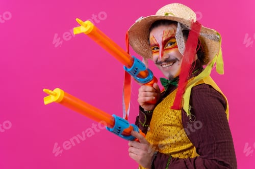 Preview: Clown with white facial makeup on a pink background, smiling with toy guns and hat