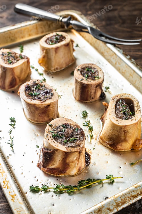Preview: Roasted marrow beef bones in baking dish. Wooden background. Top view