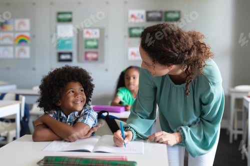 Visualização: Professora caucasiana jovem ensinando estudante do ensino fundamental afro-americano estudando na mesa