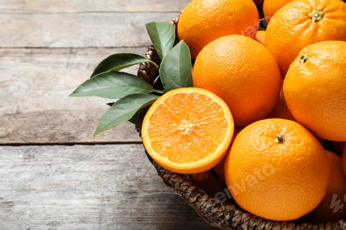 Preview: Wicker bowl with ripe oranges on wooden background, closeup. Space for text