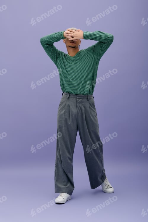Preview: Stylish young man with dyed hair poses confidently in a vibrant purple setting