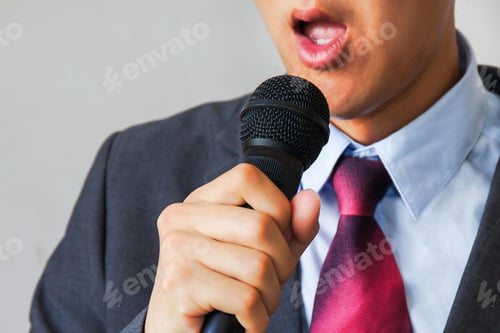 Preview: Man in business suit holding a microphone