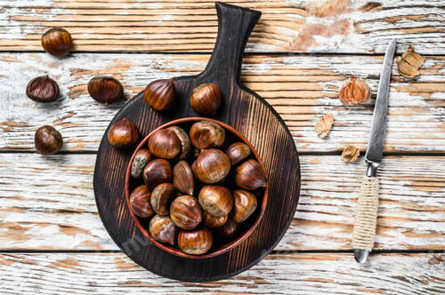 Preview: Bowl with chestnuts on a wooden table. White background. Top view