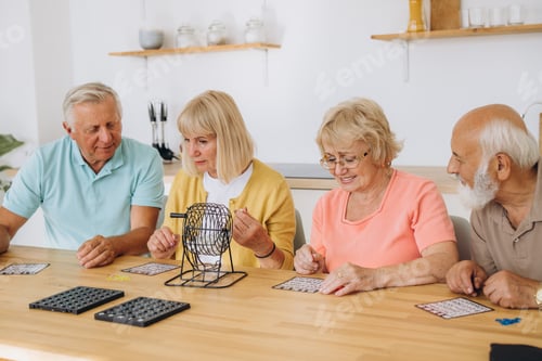 Preview: Group of four cheerful senior people playing bingo game in nursing home