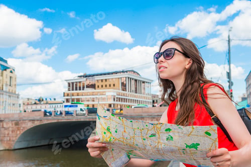 Preview: Happy young woman with a city map in Europe. Travel tourist woman with map outdoors during holidays