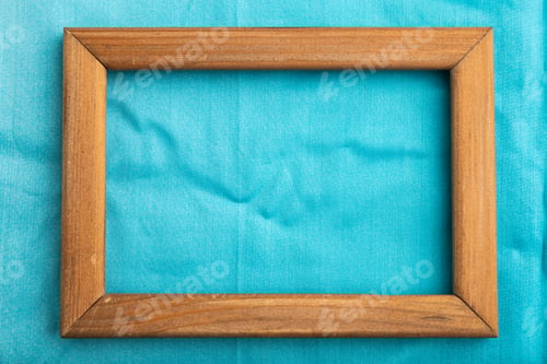Preview: Wooden frame on smooth cotton blue tissue. Top view, natural textile background.