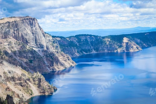 Preview: The cliffs and trees of Crater Lake National Park, Oregon. Blue sky and water.