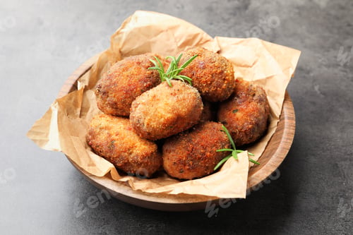 Preview: Delicious patties with rosemary in bowl on grey textured table, closeup