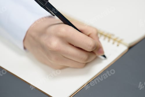 Preview: Closeup shot of hand young student lady freelancer journalist writing article using copybook in gray